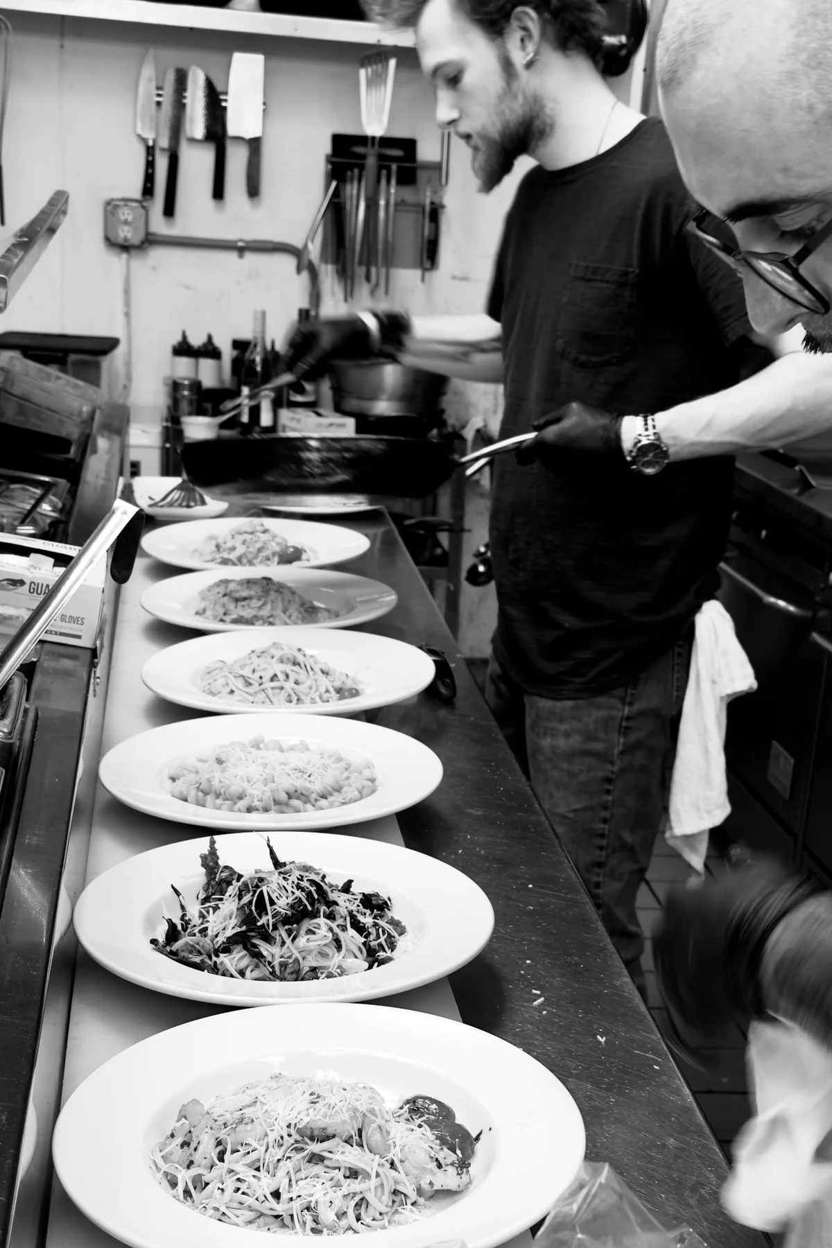 A line of finished plates beside the cooks at the working range.